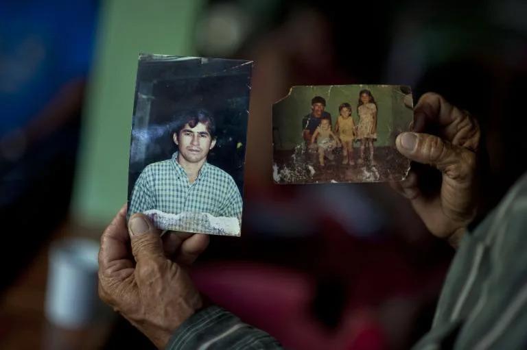 A person holding worn family photographs that are beginning to fade